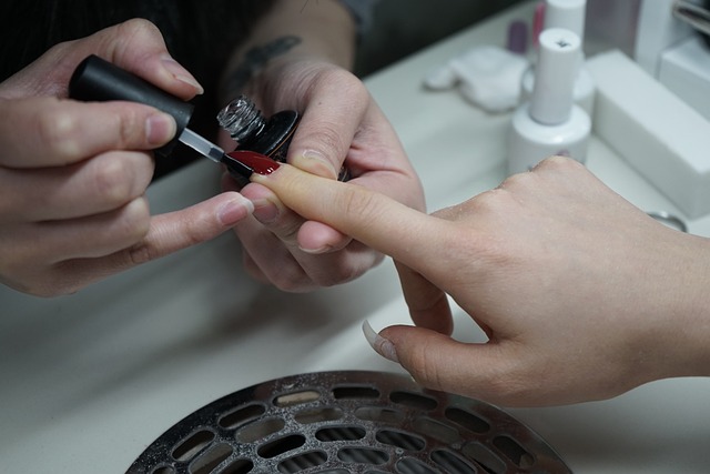 An image of a manicurist applying a top coat.