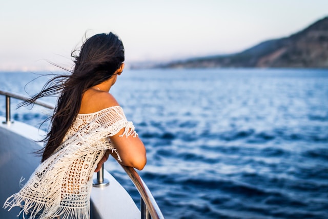 An image of a woman leaning on the balcony of a cruise ship.