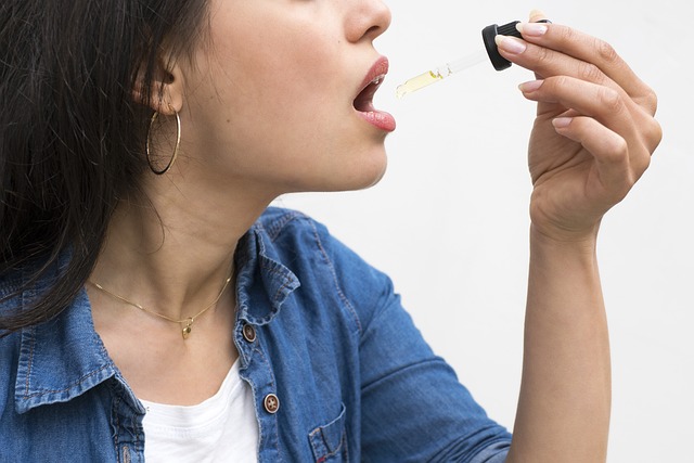 An image of a woman placing CBD oil under the tongue.