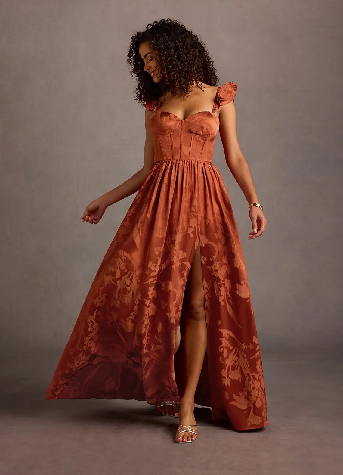 An image of examples of fall wedding guest dresses. A woman in an orange dress from Azazie.