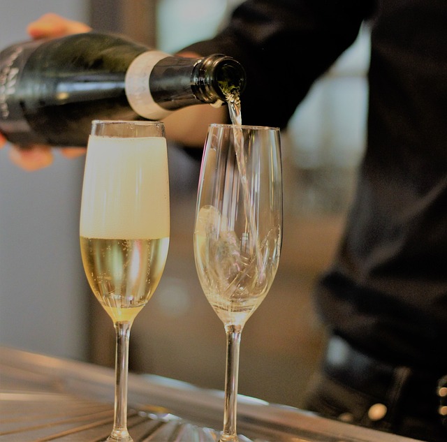 An image of champagne being poured in two champagne flutes as housewarming gift ideas.