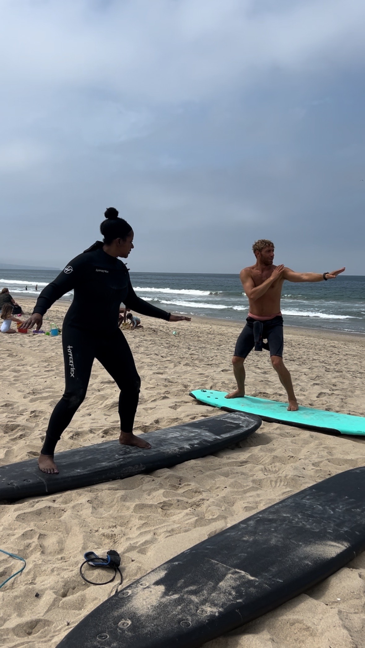 An image of lifestyle blogger Ariel taking a surfing lesson from Nick during Happy Yoga Beach Sessions.