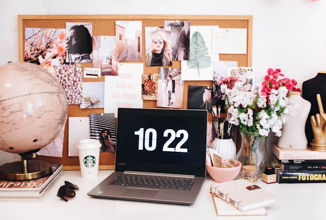 An image of a home office desk with candles, flowers and photos on it.