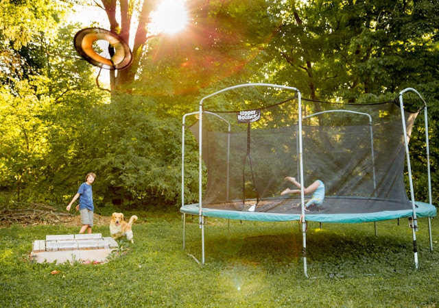 An image of two children playing on a trampoline.