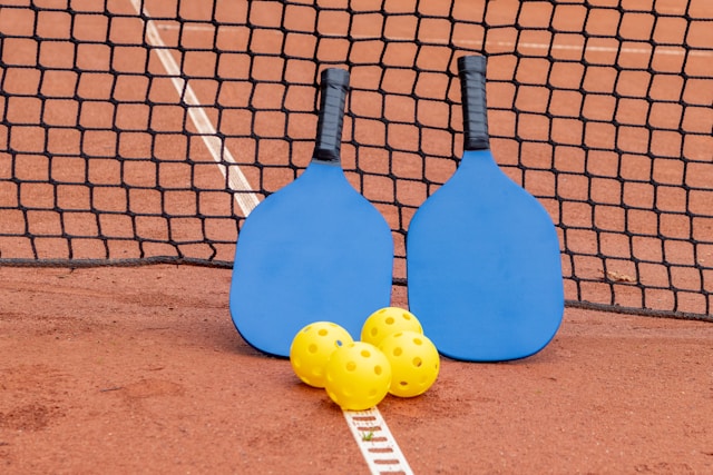 An image of two pickleball paddles and 4 pickleball balls.