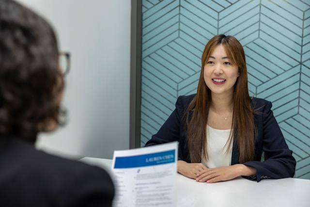 An image of a woman being interviewed for a job with her resume.