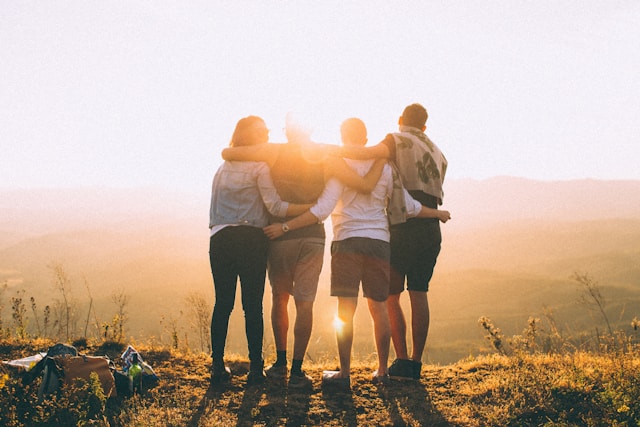 An image of people who met while traveling. They are posing for a photo arm in arm.