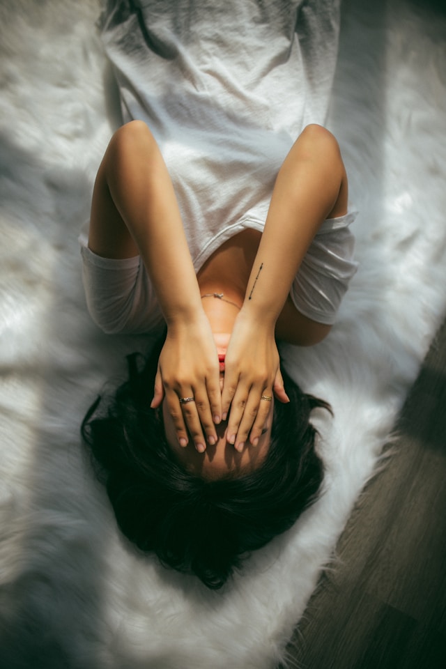 An image of a woman laying on a bed stressed out. 