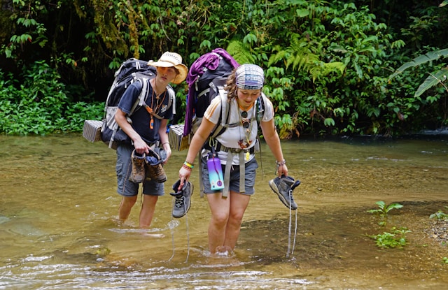 An image of two backpackers crossing a creek.