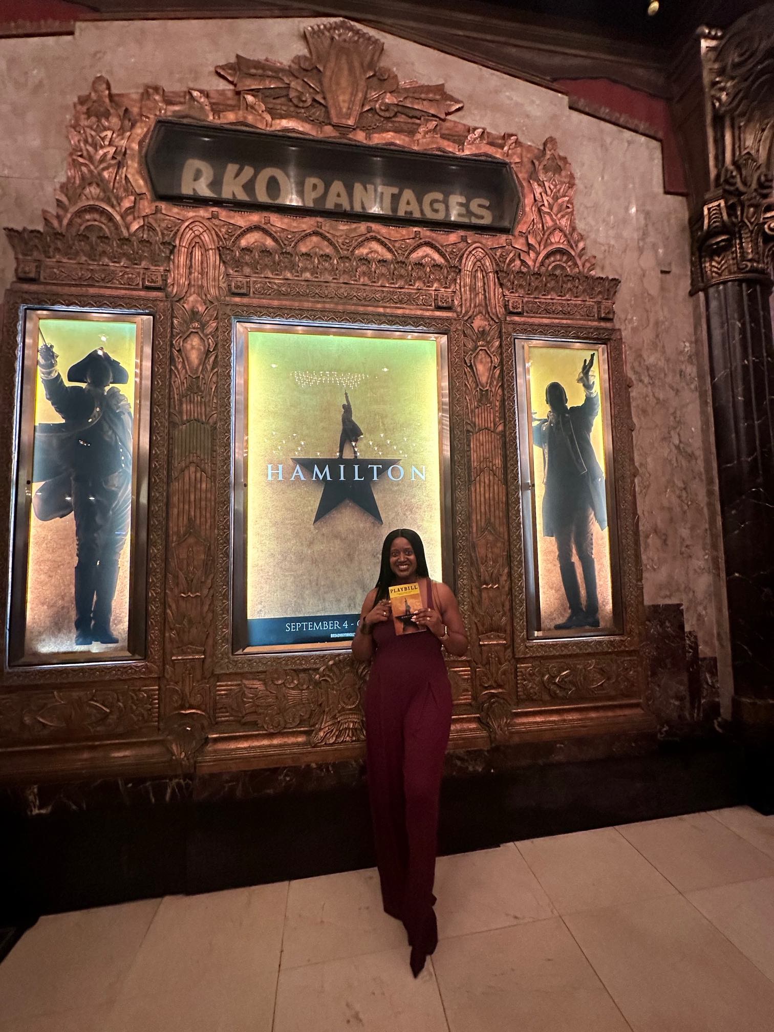 An image of lifestyle blogger Ariel at the Pantages in front of a Hamilton poster.