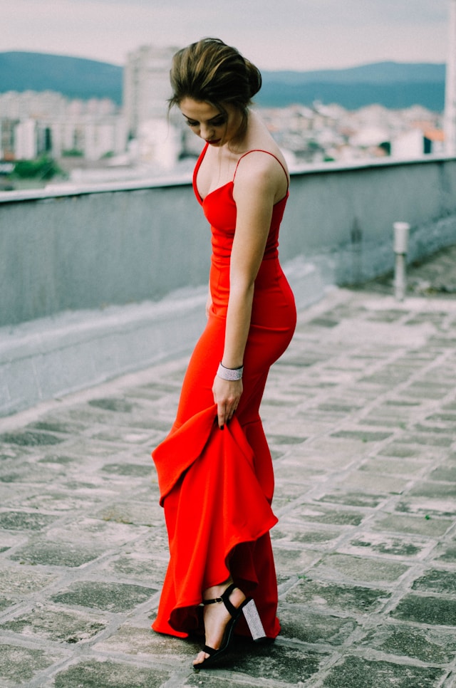 An image of a woman in a red cocktail dress with block heels.