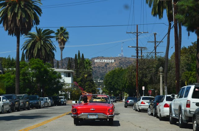 An image of the Hollywood sign with a red convertible in front of it.