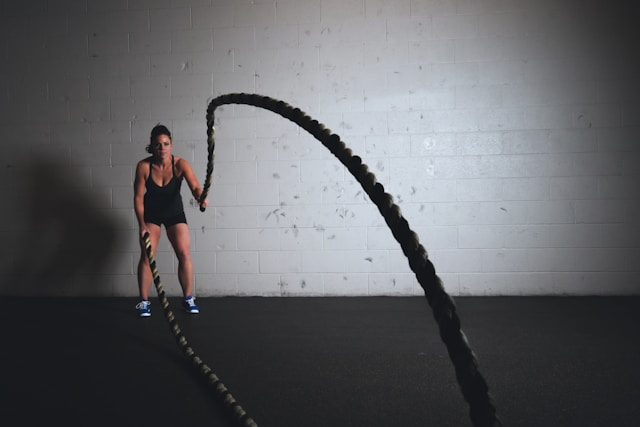 An image of a woman working out with battle ropes.