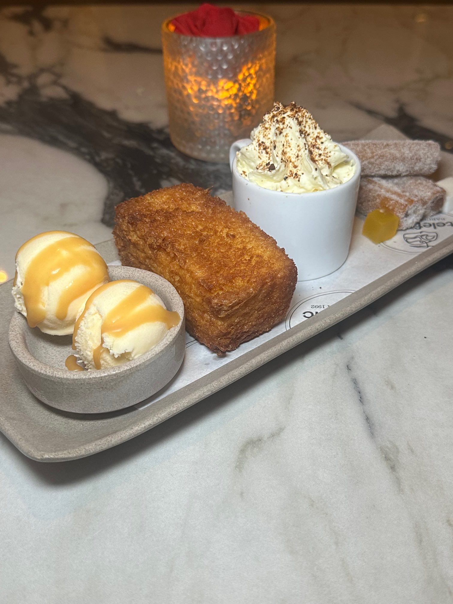 An image of the Trio of Desserts: traditional churros with chocolate, a decadent torrija (Spanish bread pudding), and silky flan, paired with robust Spanish coffee.