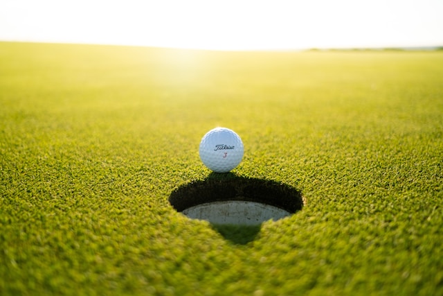 An image of a golf ball at a hole on a golf course.