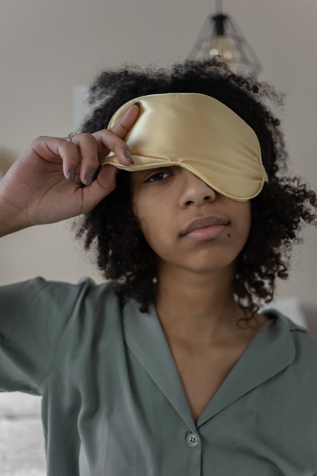 An image of a woman getting ready for bed wearing a sleep mask.