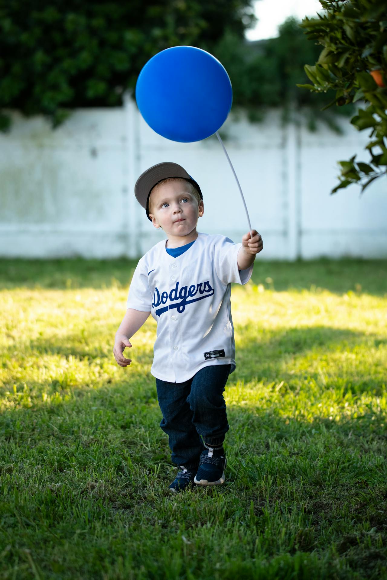 An image of a little boy in a Dodgers jersey holding a blue balloon.