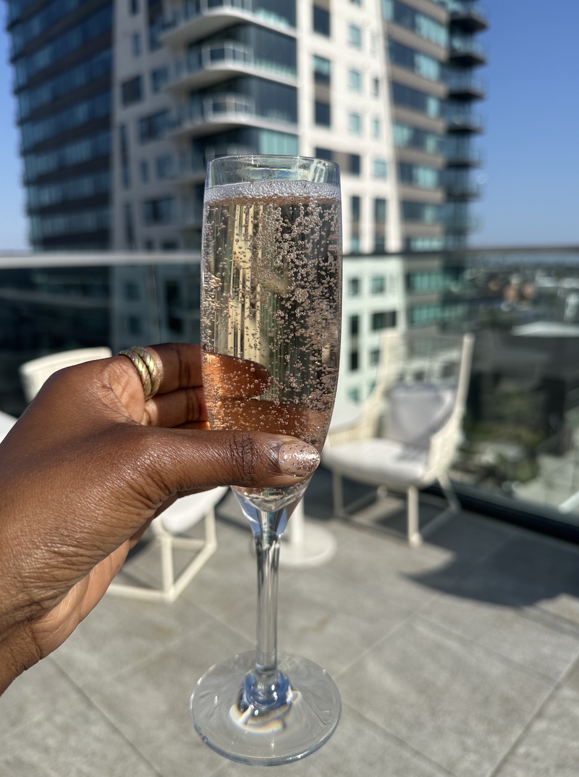 An image of someone holding a glass of champagne on the Godfrey Hotel rooftop.