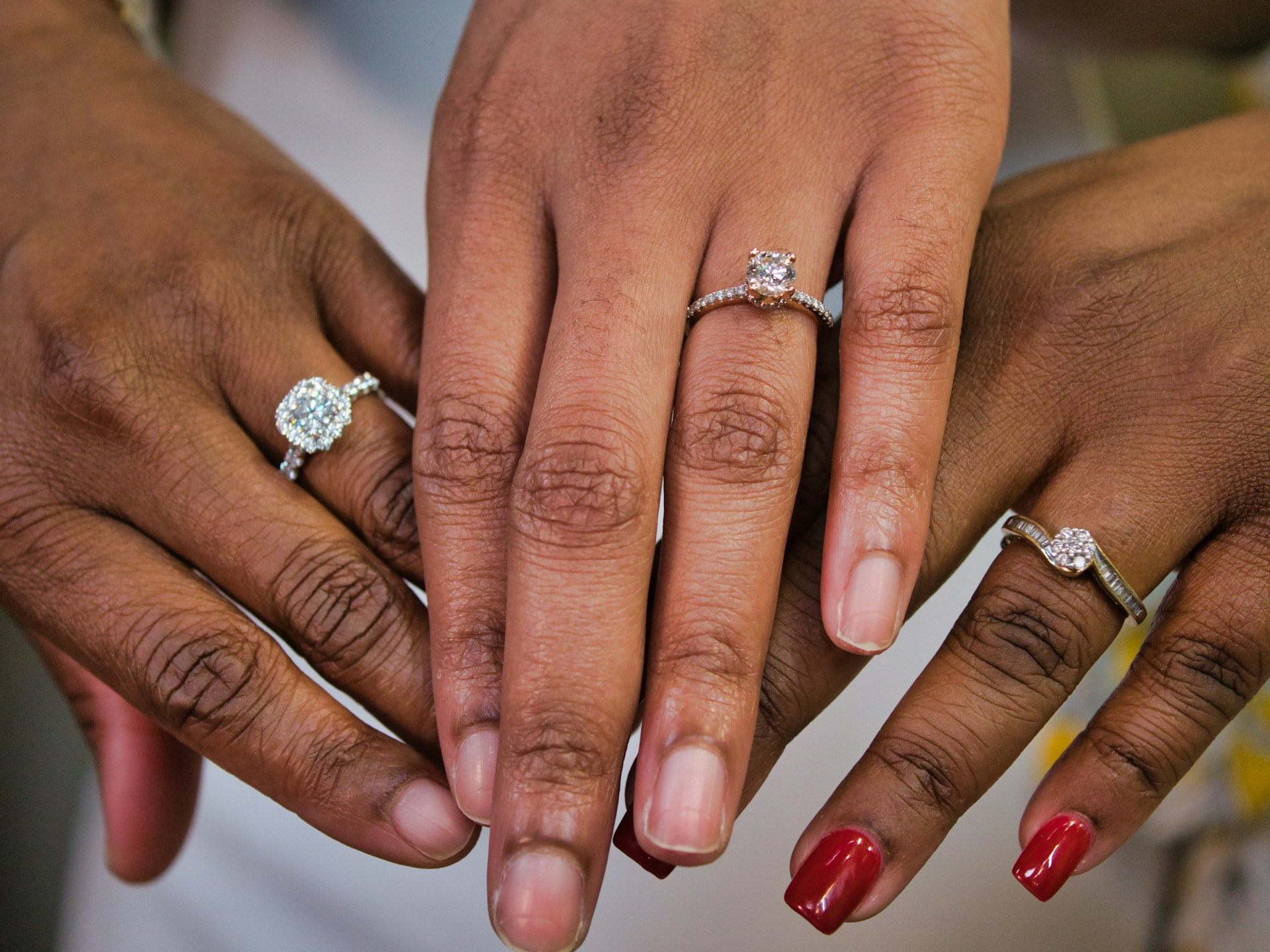 An image of three hands wearing diamond rings.