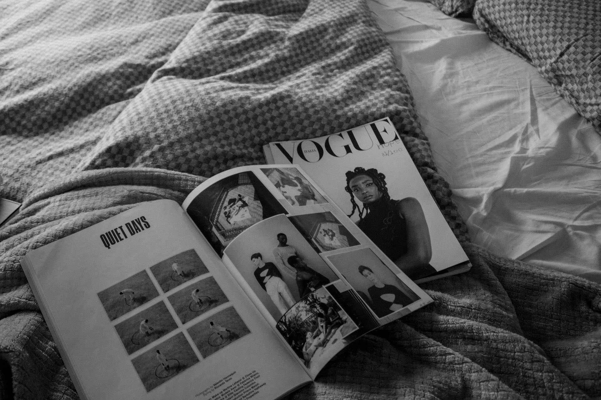 An image of fashion magazines laid out on a bed.