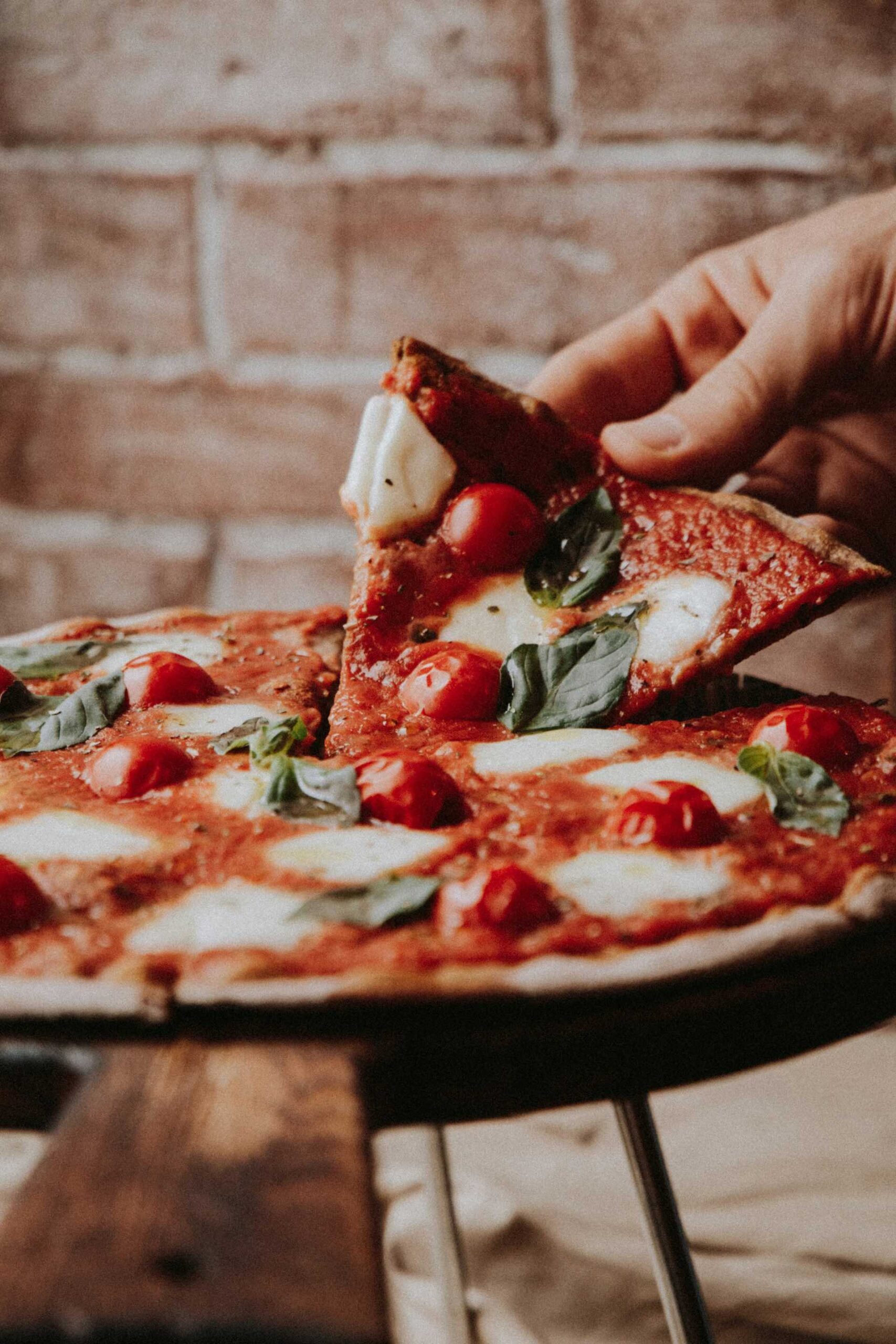 An image of someone grabbing a slice of pizza.
