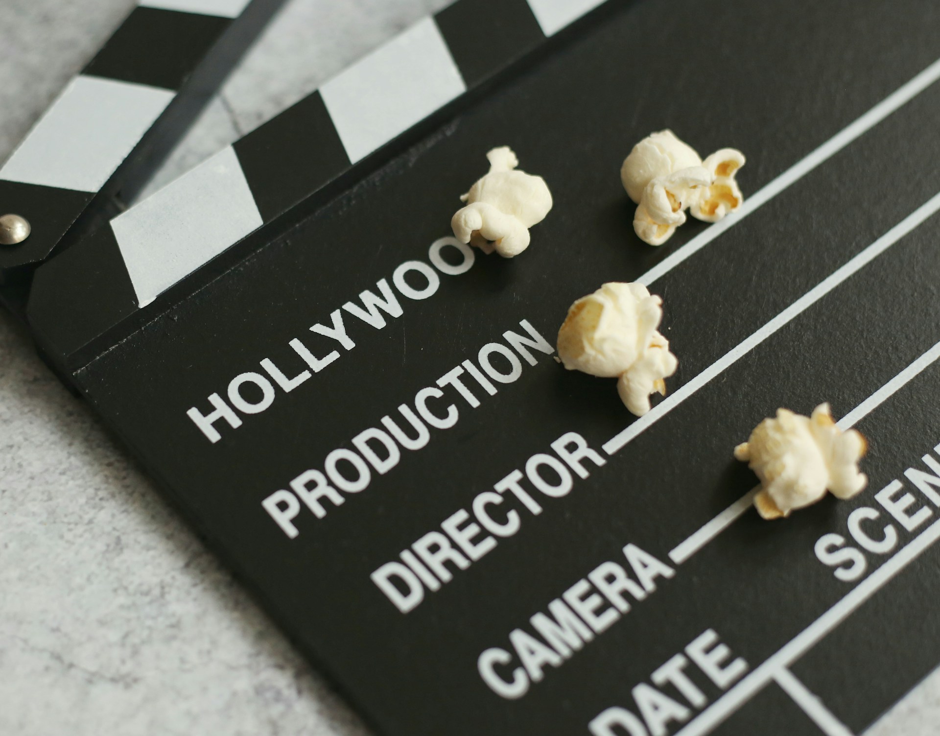 An image of a movie clap board and popcorn kernels.