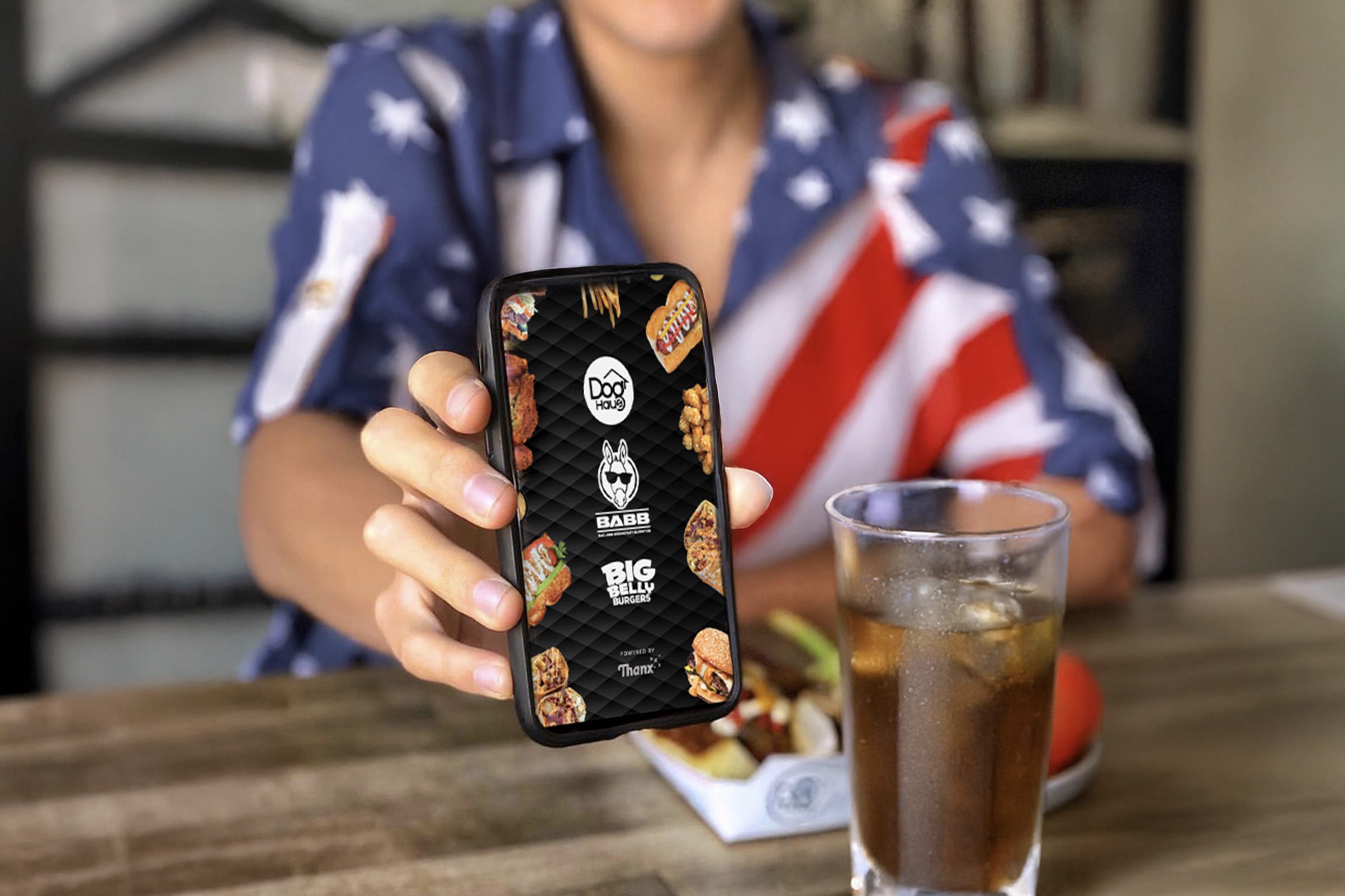 An image of someone holding a phone with the Doh Haus app.