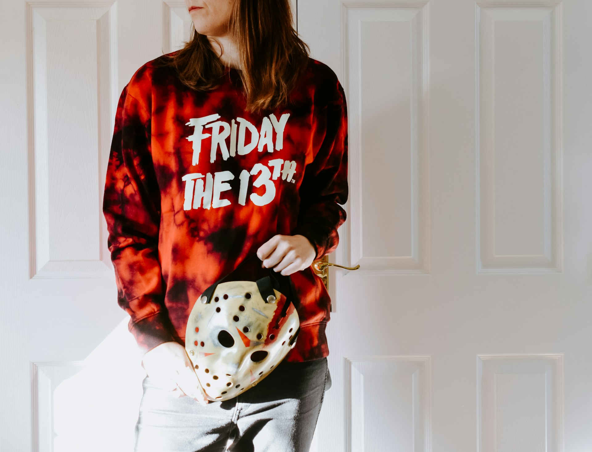 An image of someone wearing a Friday the 13th shirt and holding a Jason Voorhees mask.