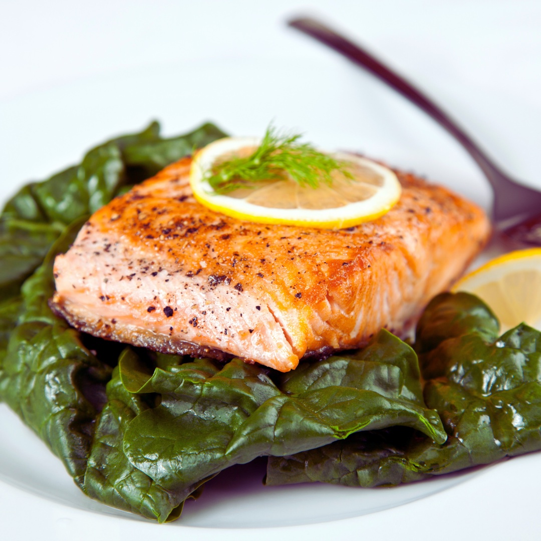An image of a plate of salmon and leafy greens.