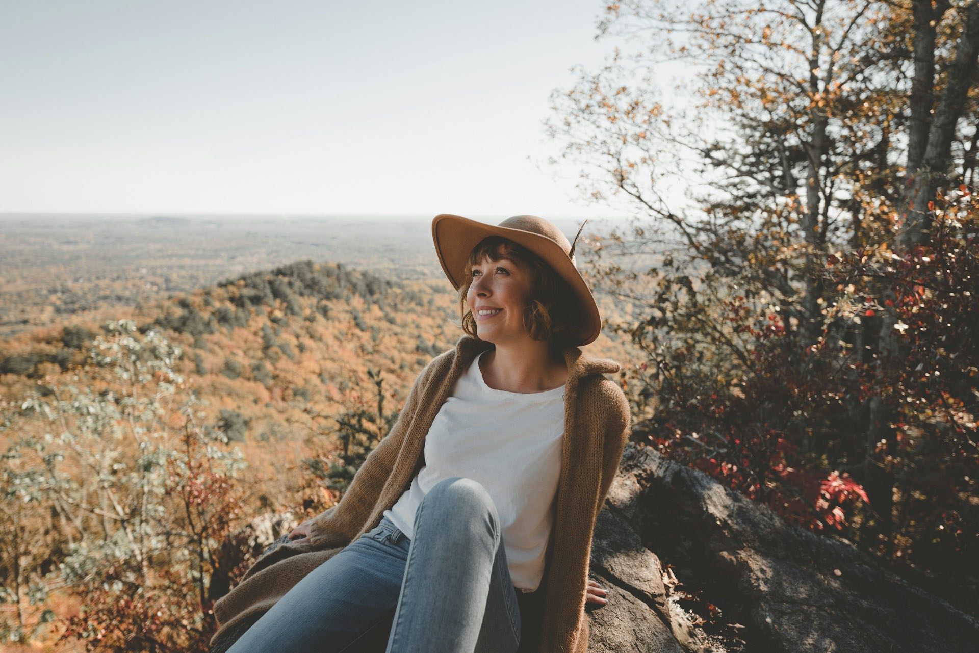 An image of a woman in a fall outfit sitting on the ground.