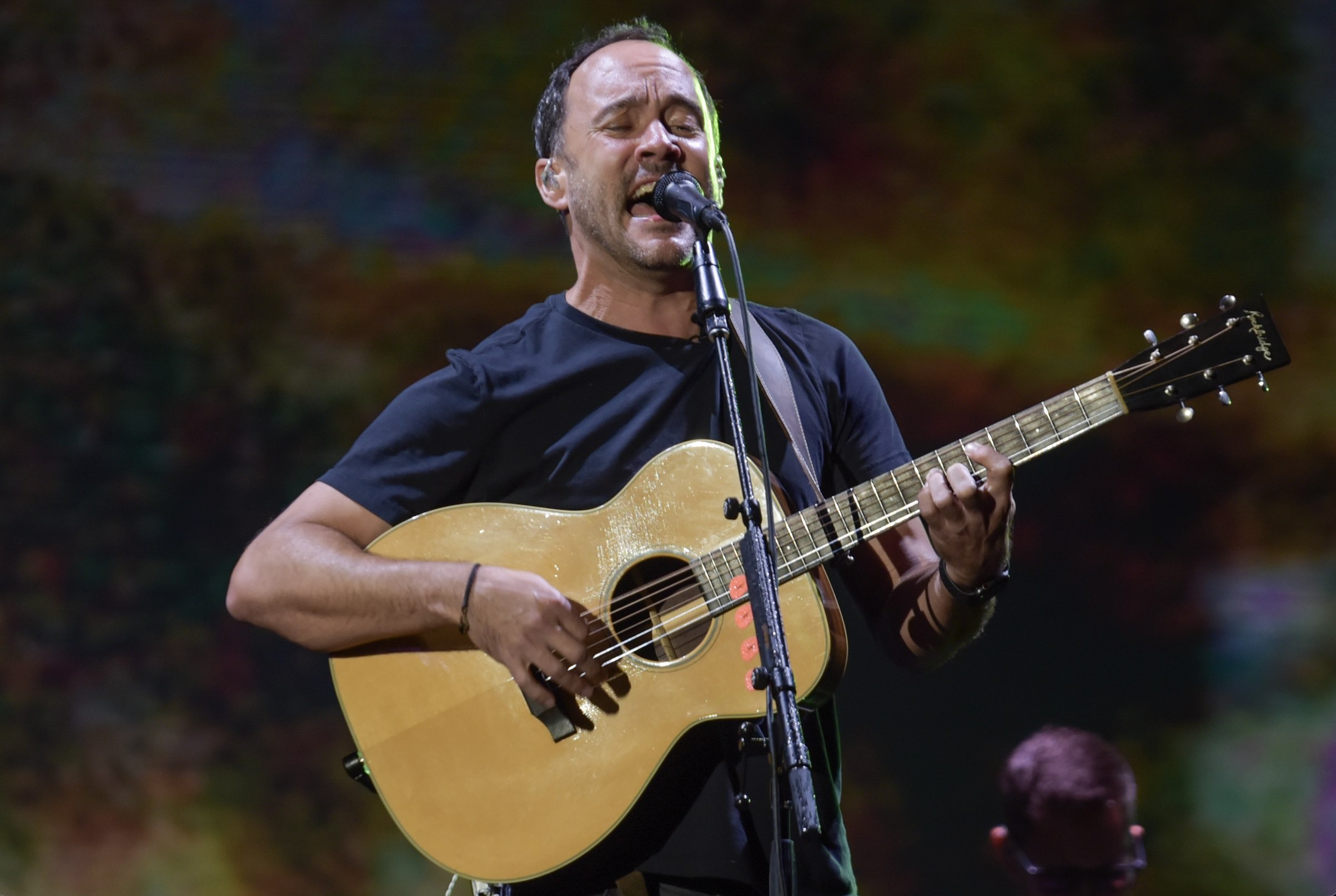 An image of Dave Matthews holding a guitar on stage.