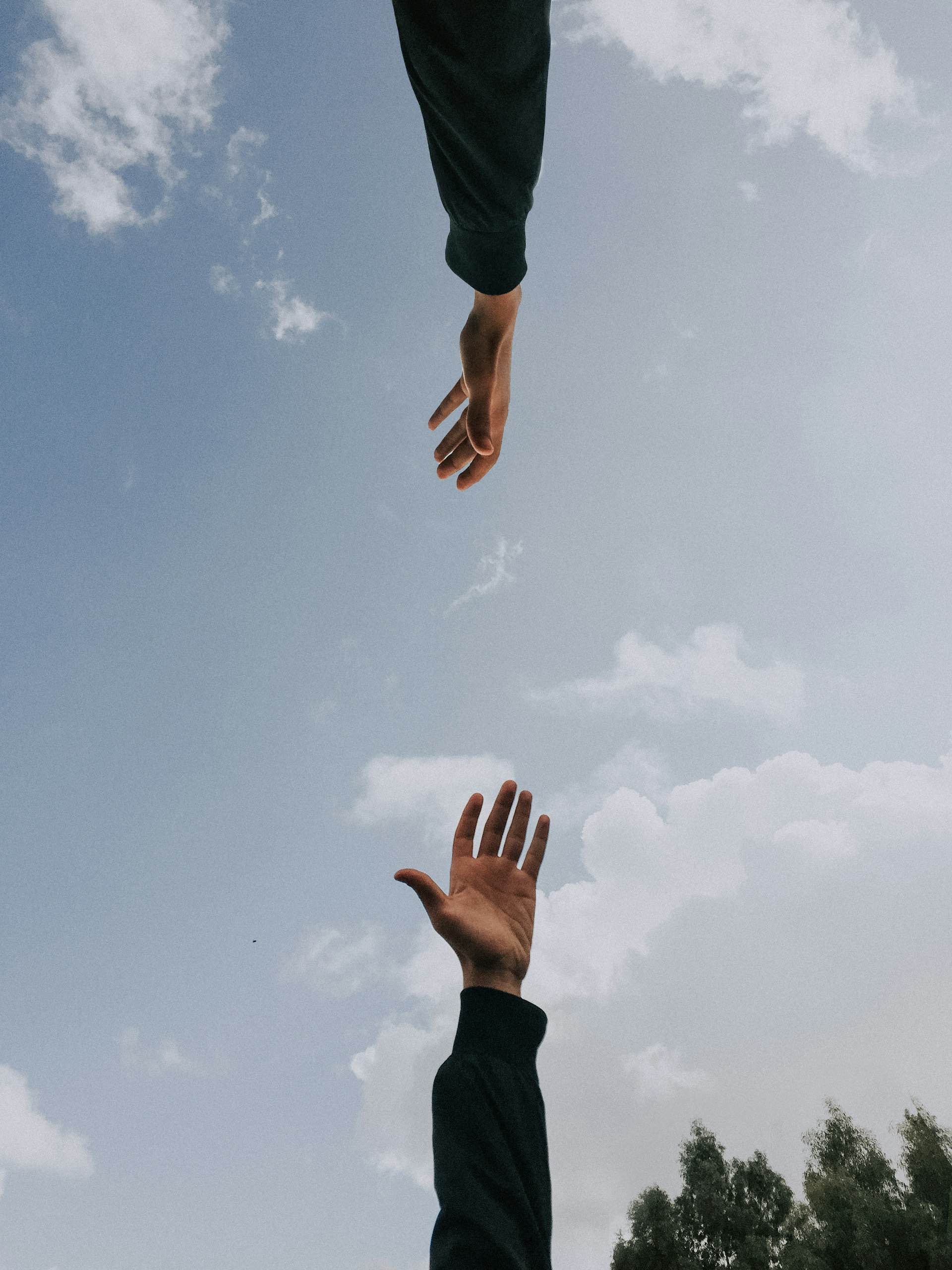 An image of two hands reaching towards each other.