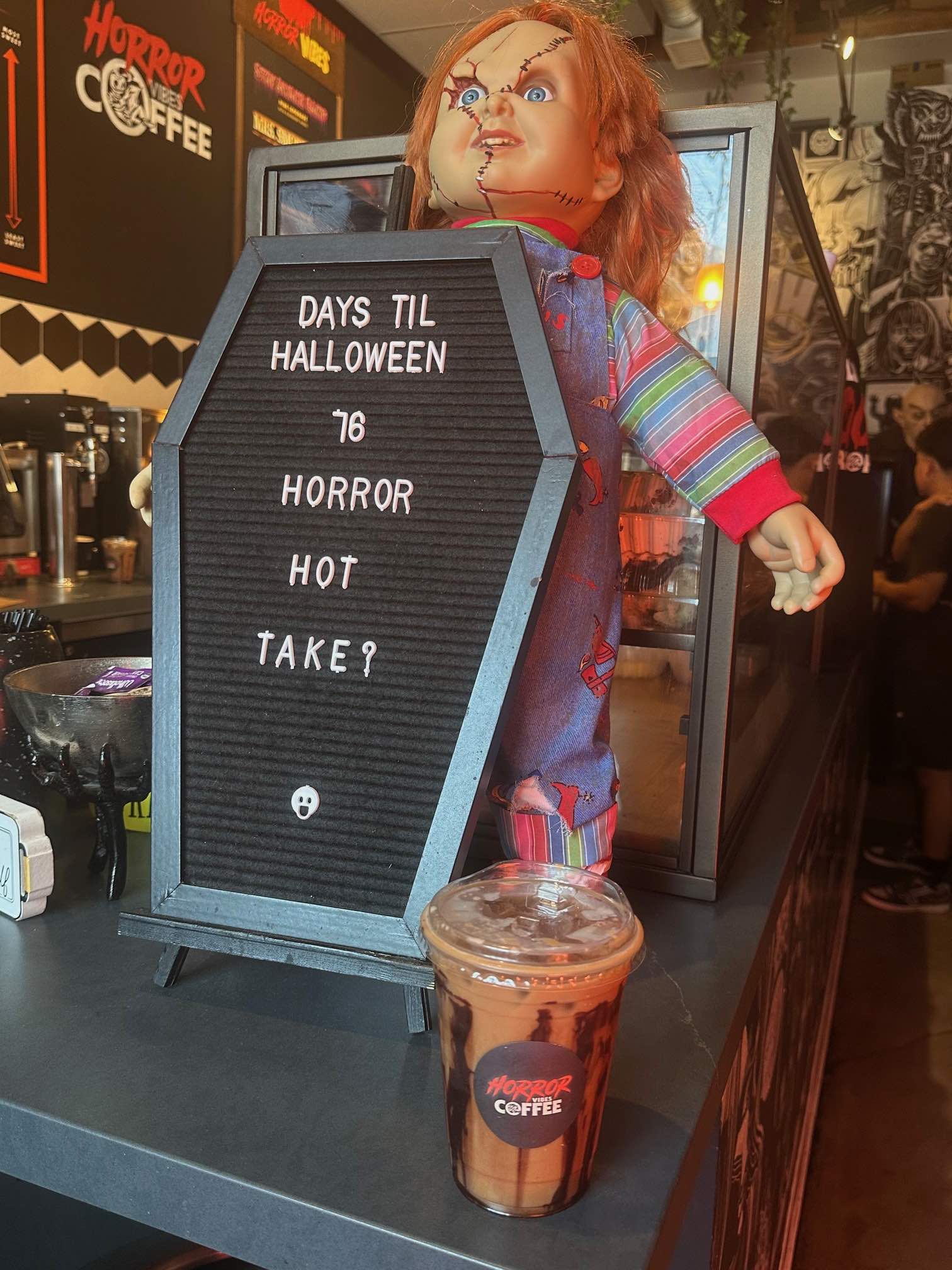 An image of a Chucky Doll, coffin and iced coffee.