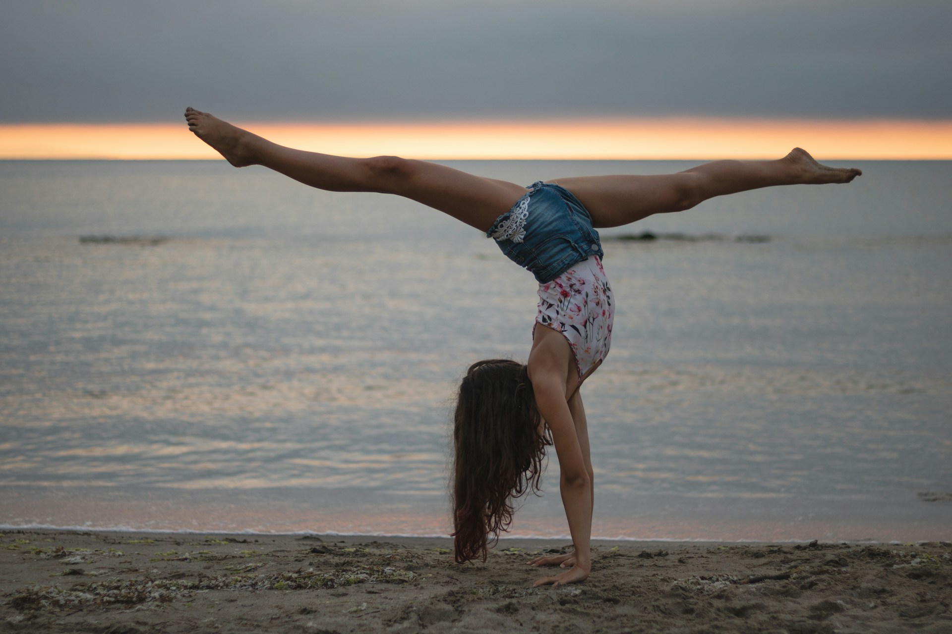 An image of a woman doing a handstand at the beach.