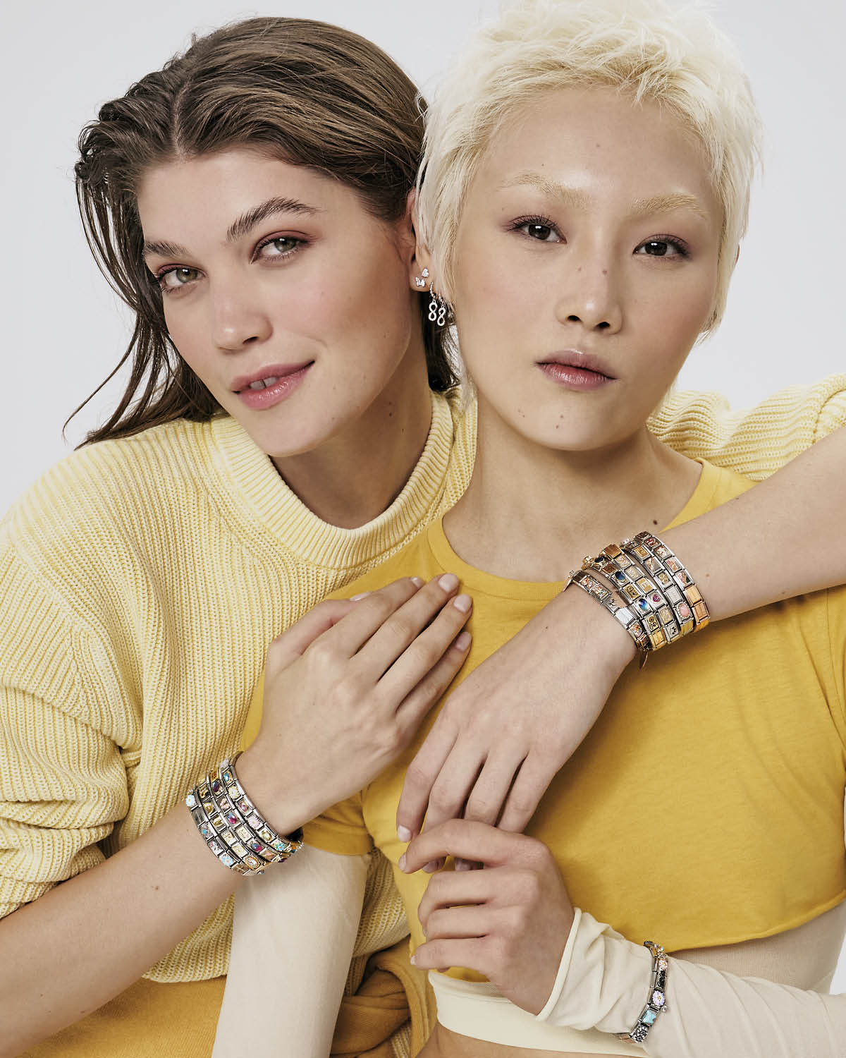 An image of two women in yellow wearing bracelets.