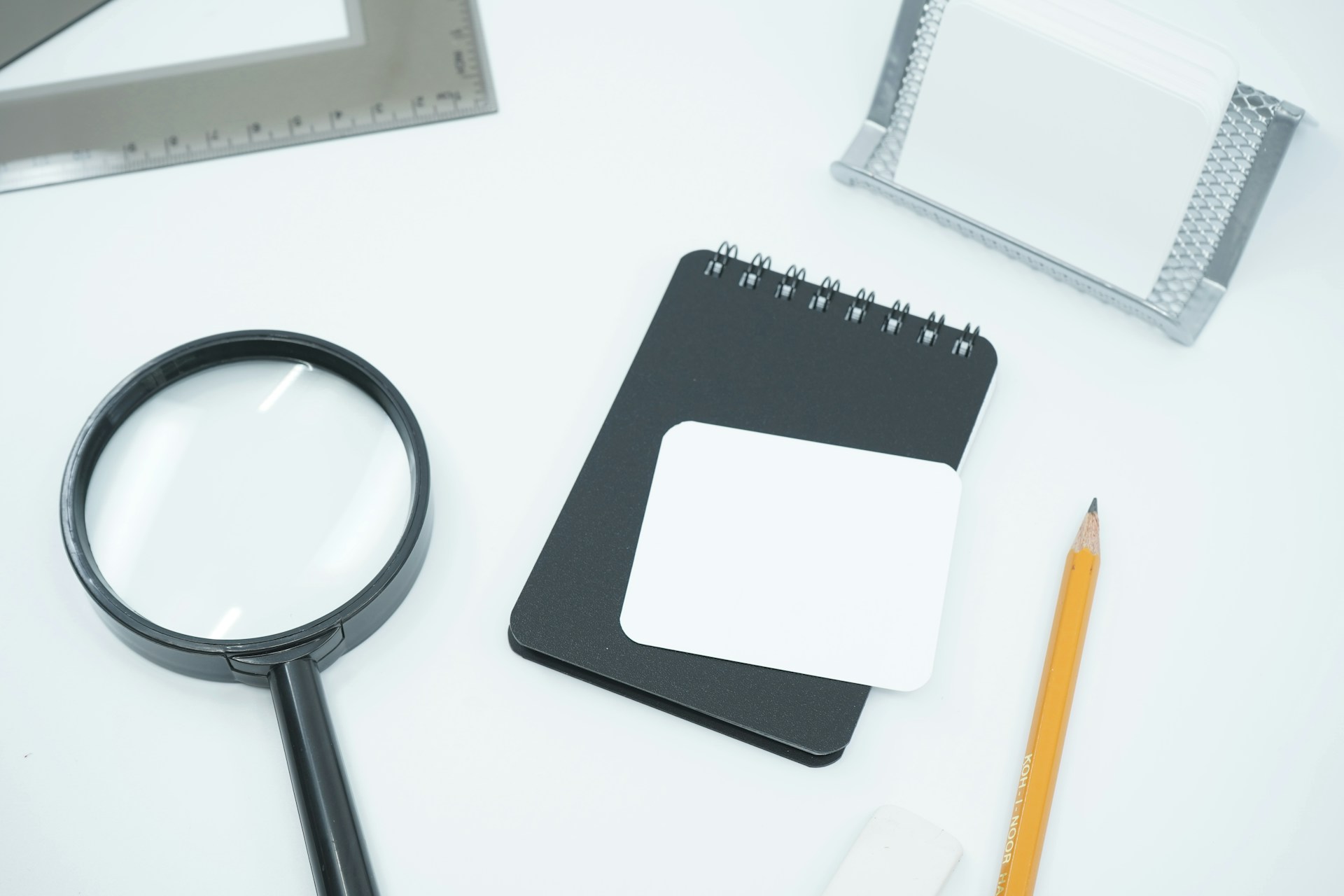 An image of a detective kit: magnifying glass, notepad, pencil