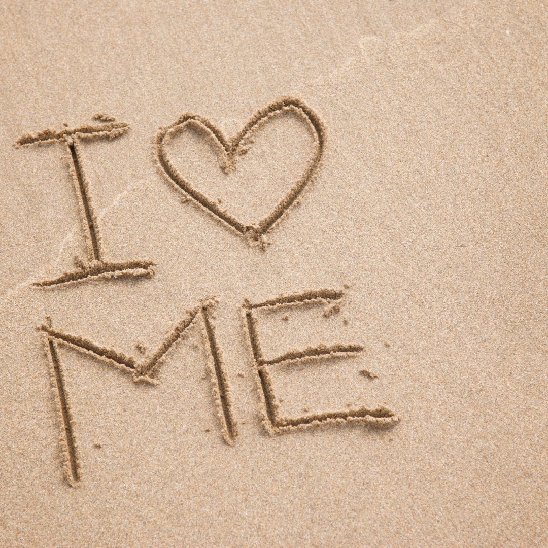 An image of the words I love me written in the sand.