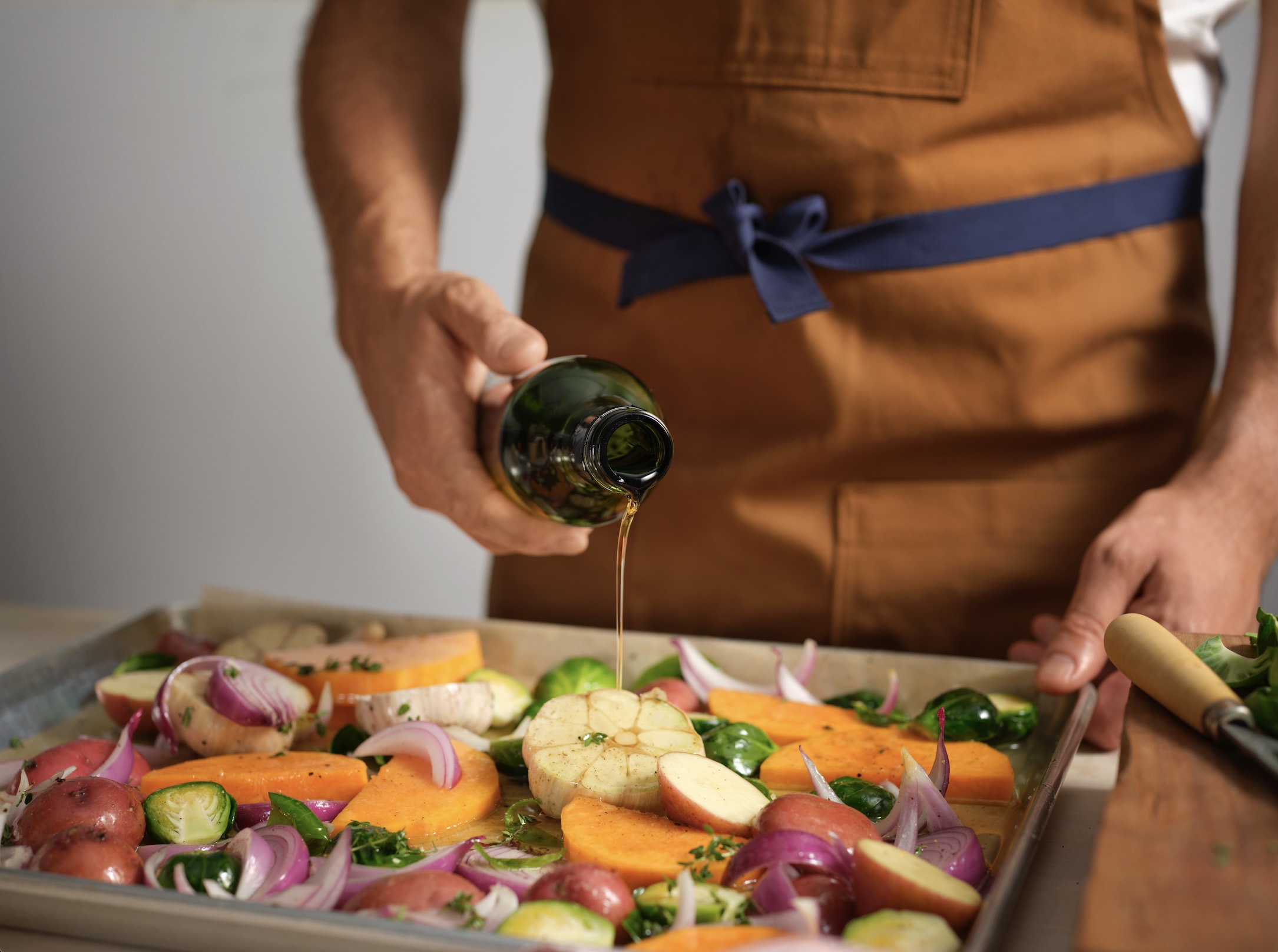 An image of someone drizzling Smash Kitchen oil on fresh veggies.
