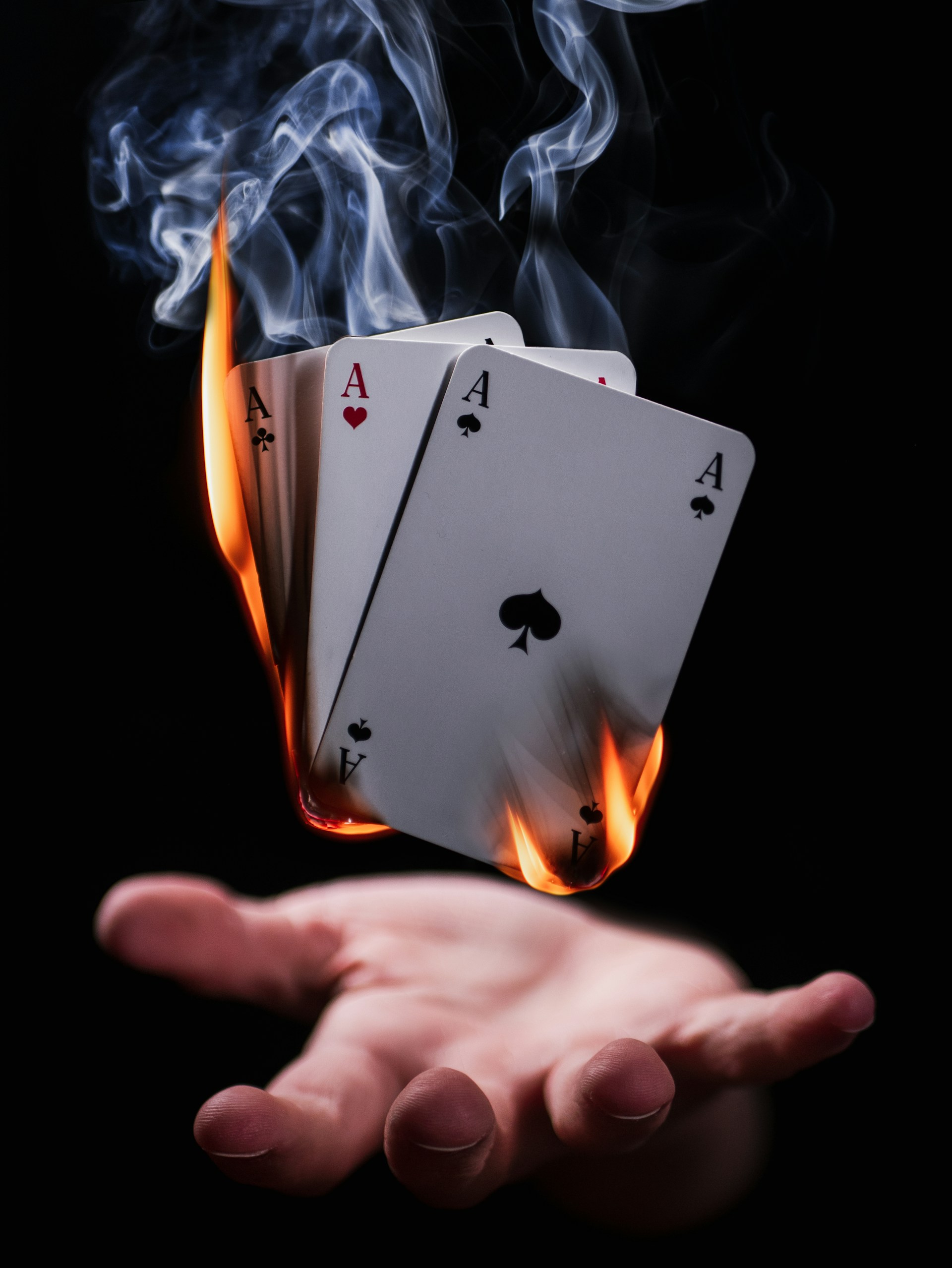 An image of a magician holding a flaming deck of playing cards.