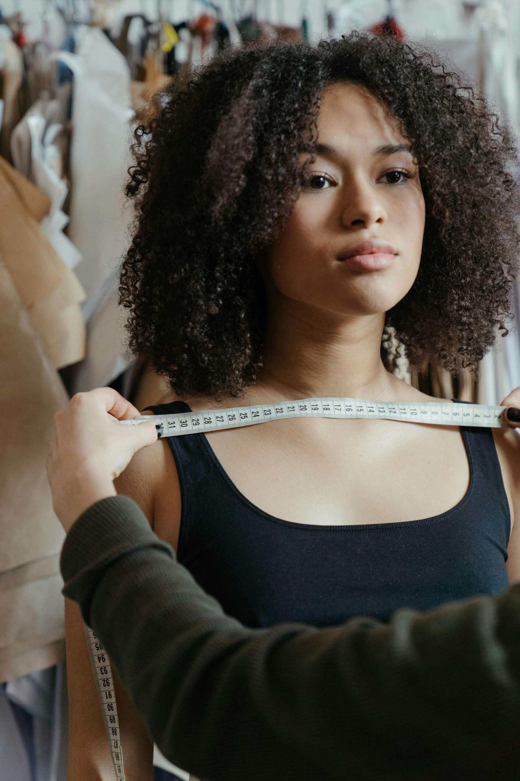 An image of a woman getting measured at a tailor.