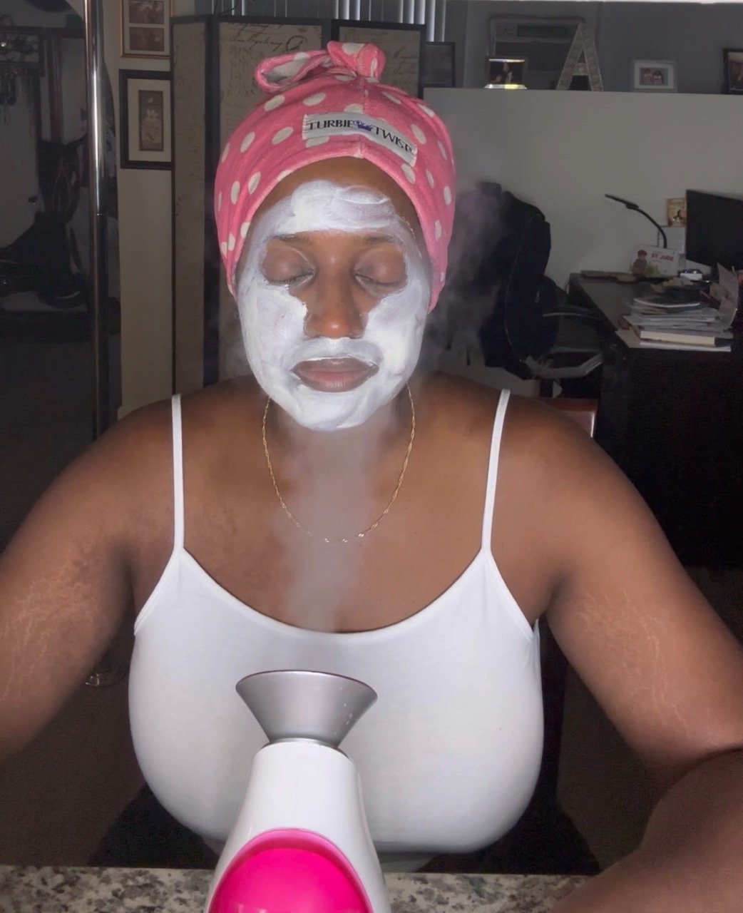 An image of lifestyle blogger Ariel steaming her face with a facial steamer.