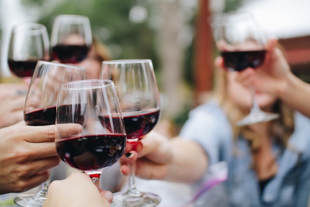 An image of people holding glasses of red wine.