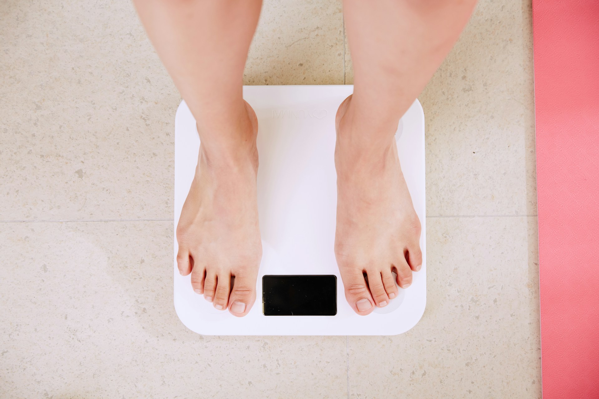 AN image of a person weighing themself on a scale.