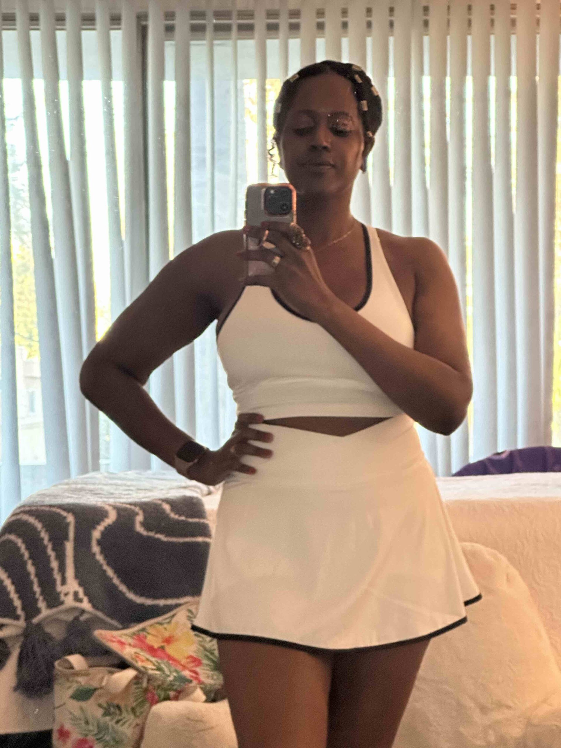 An image of lifestyle blogger Ariel Johns wearing the two-piece Lux Tank and Crossover Skort in white.