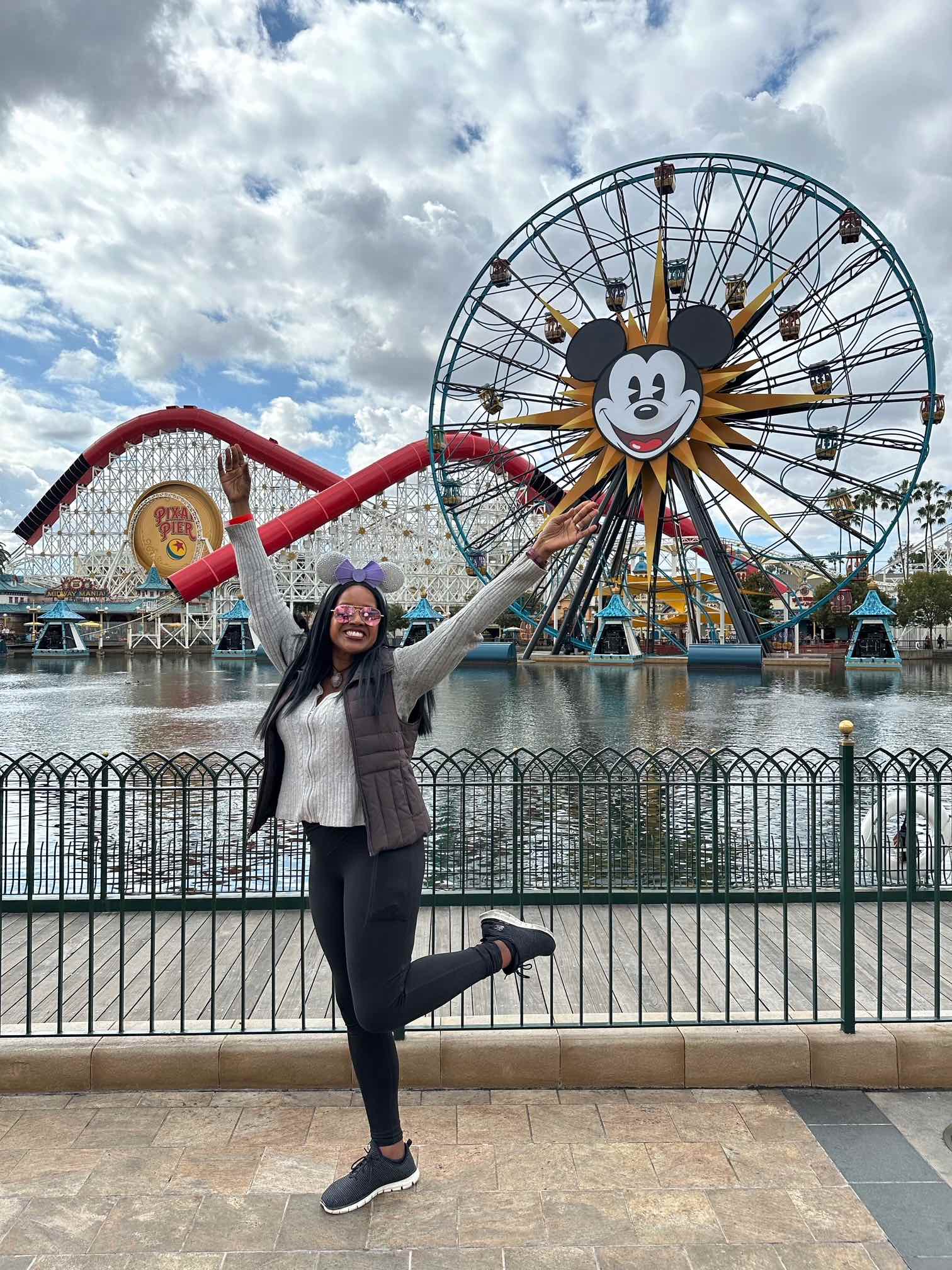An image of lifestyle blogger Ariel Johns posing in front of the ferris wheel at Disney California Adventure.