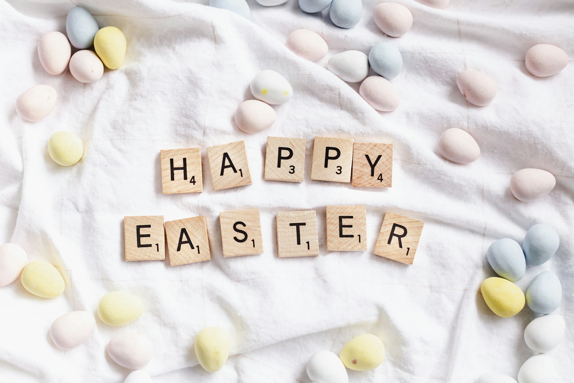 An image of letter tiles that spell Happy Easter surrounded by mini chocolate eggs.