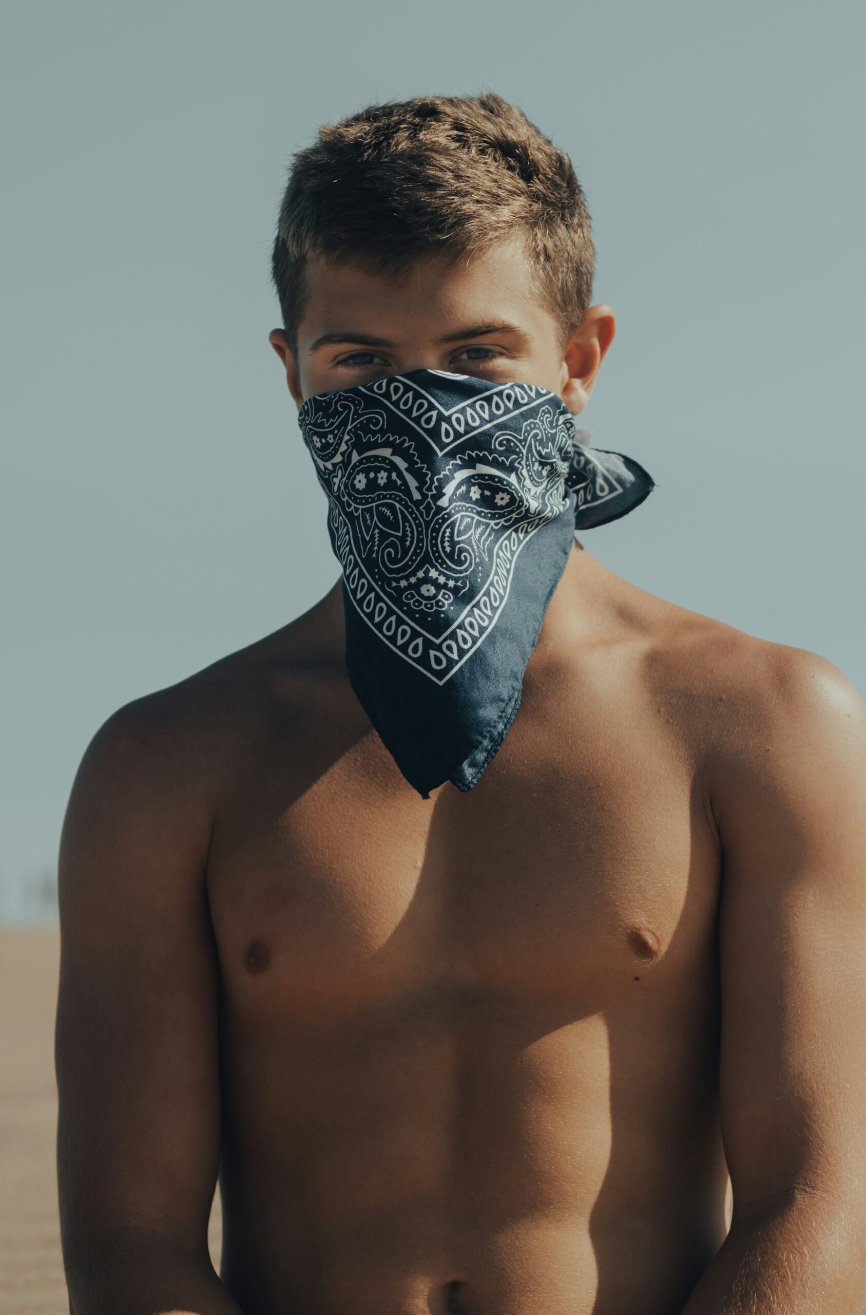 An image of an attractive man wearing a bandana ties around his face.