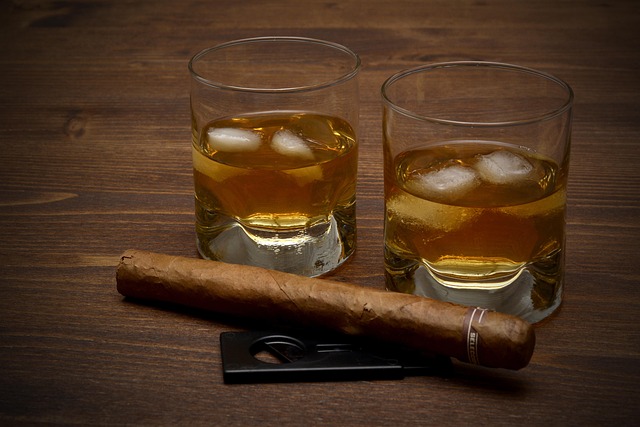 An image of two glasses of whiskey and a cigar.