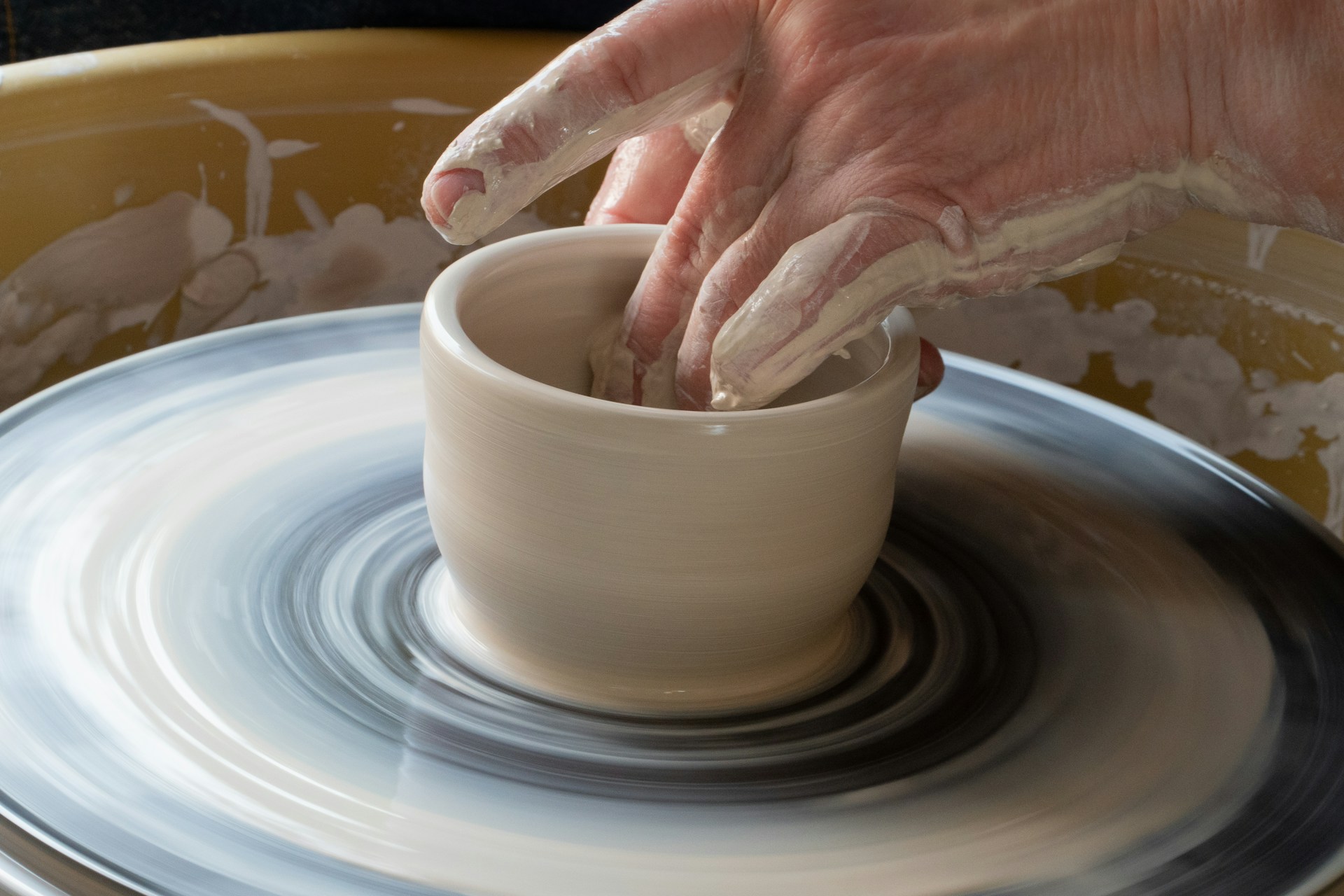 An image of someone making a bowl in a pottery class.