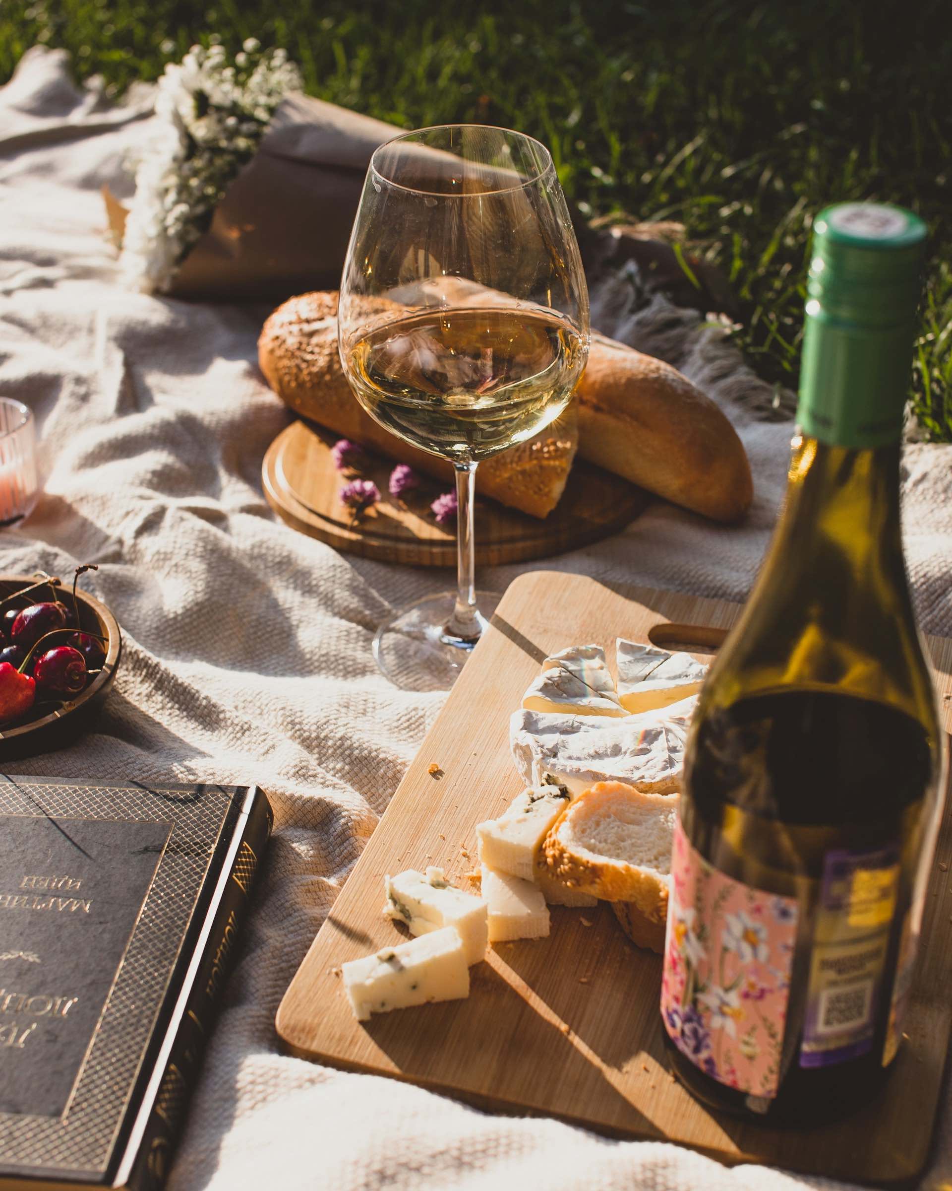 An image of a blanket covered in wine and cheese.